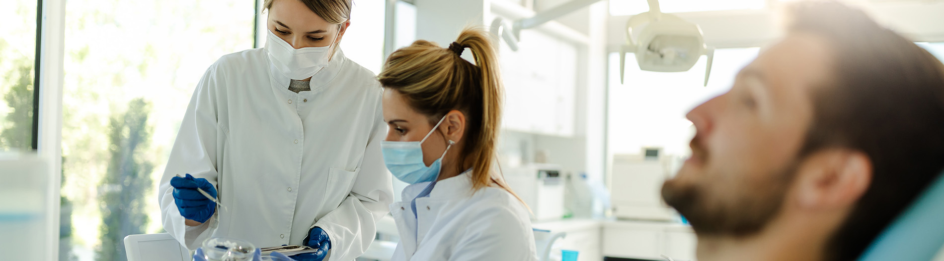 The image shows a modern dental clinic interior with various pieces of equipment, including a dental chair and an X-ray machine.