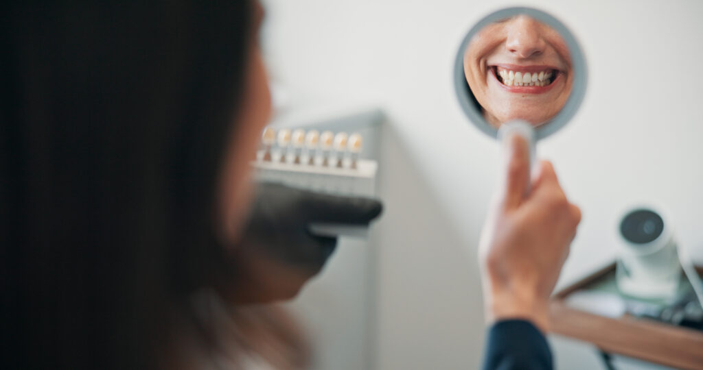 Happy woman, mirror or patient in dental clinic for crown, veneers or medical procedure. Reflection, smile or person with implant in oral exam for dentistry, teeth whitening or cosmetics treatment.