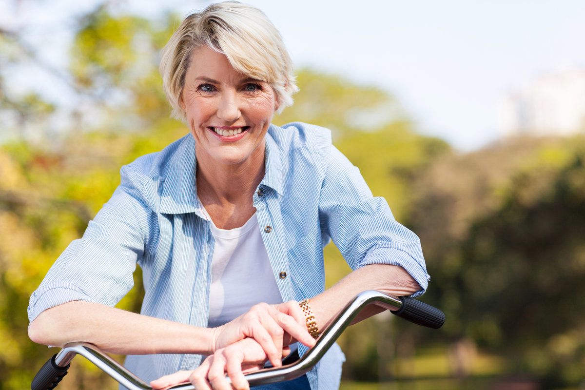 Smiling woman with bicycle outdoors